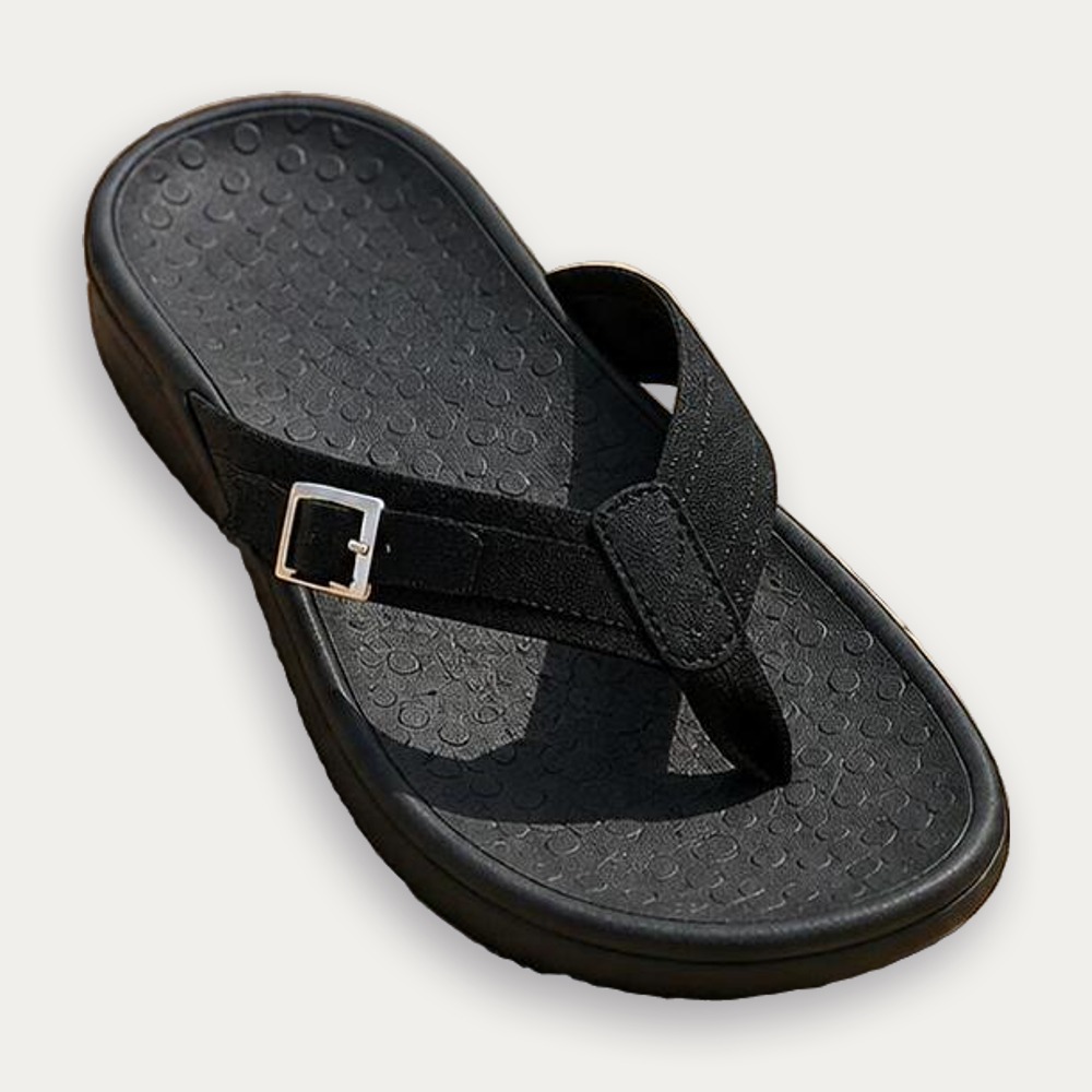 Une paire de sandales ouvertes orthopédiques à talon rembourré pour femme noires, avec bride et boucle, posée sur fond clair.